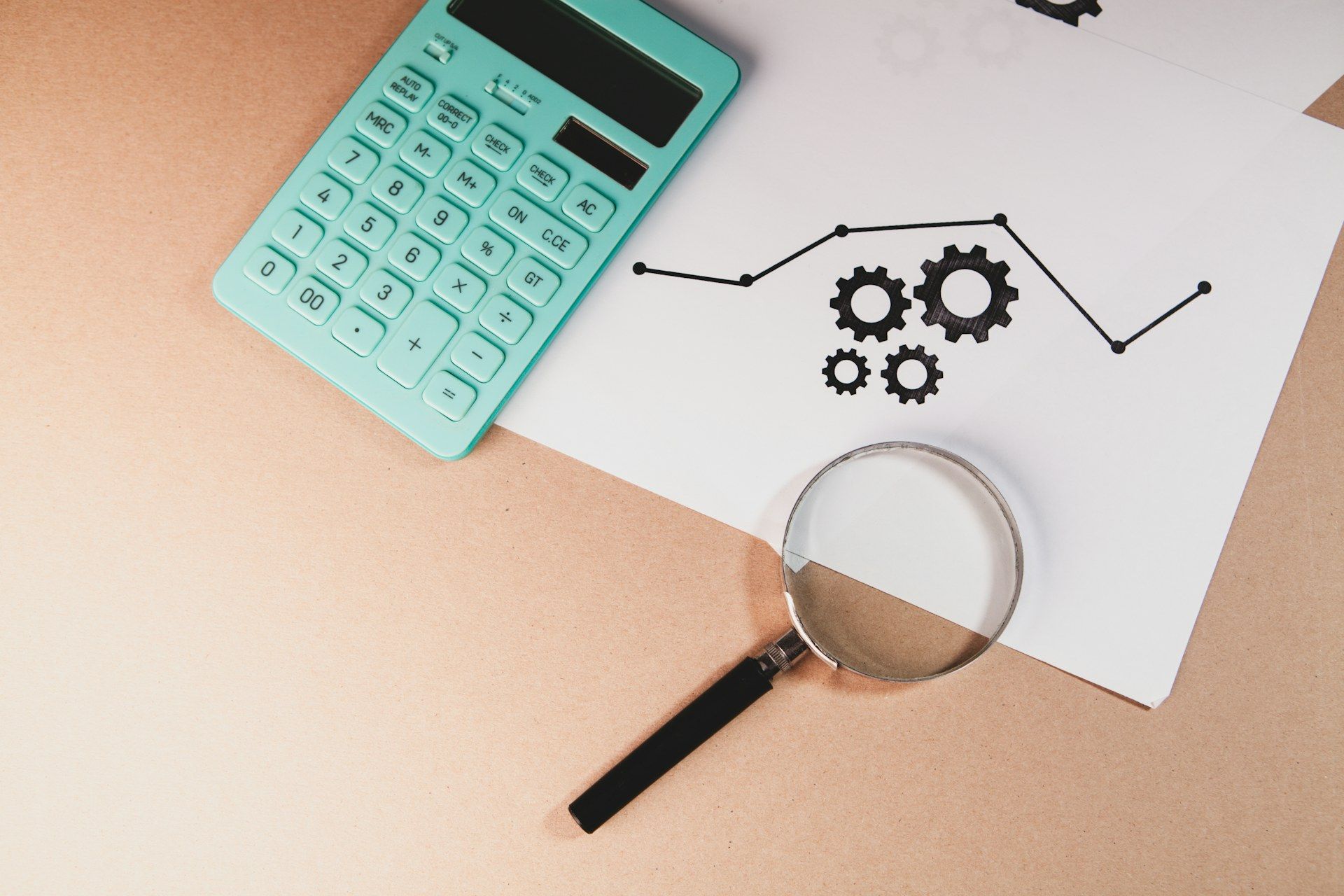 Calculadora, lupa e relatório sobre a mesa, ilustrando a análise de contratos e cálculos em ação de cobrança bancária