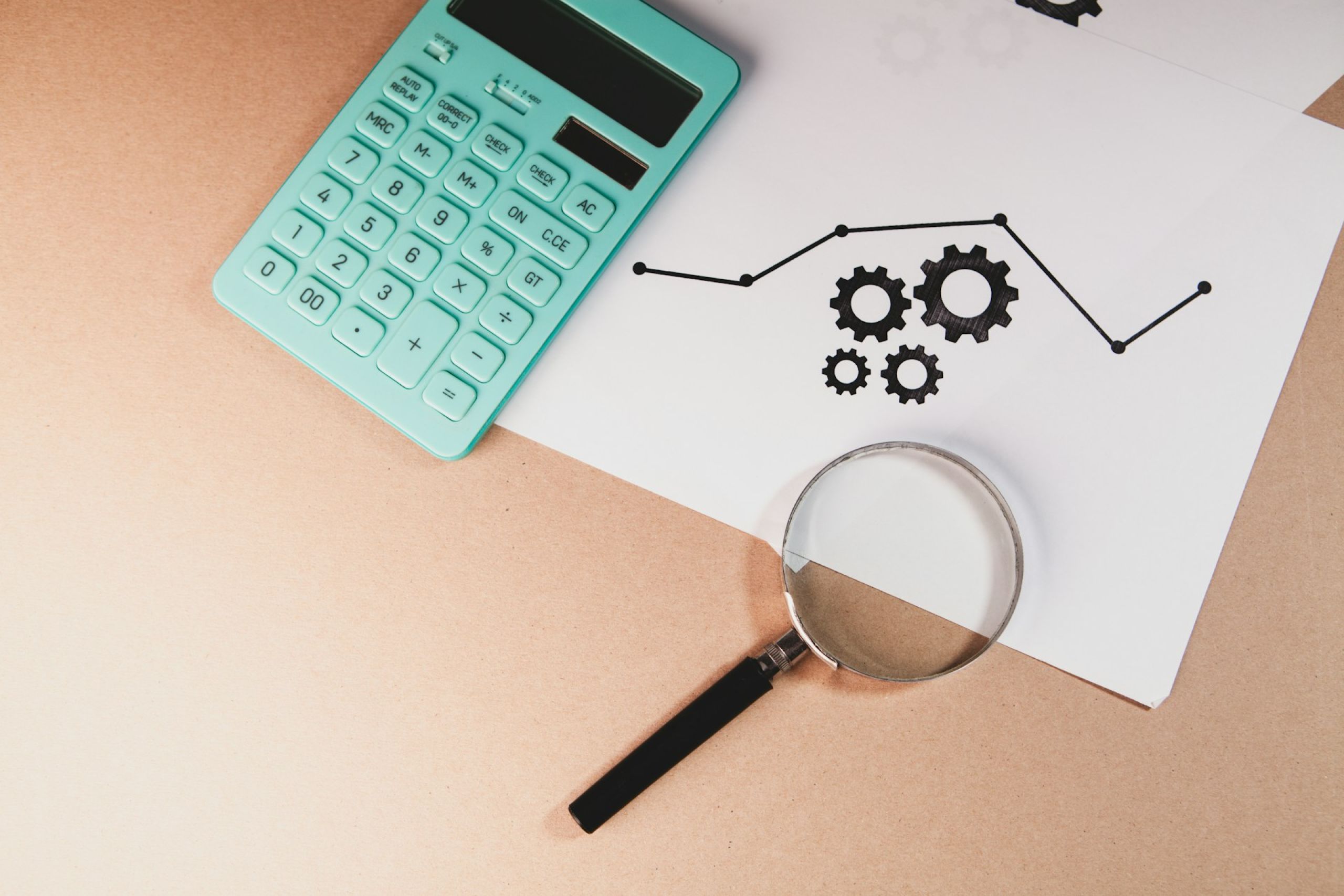 Calculadora, lupa e relatório sobre a mesa, ilustrando a análise de contratos e cálculos em ação de cobrança bancária