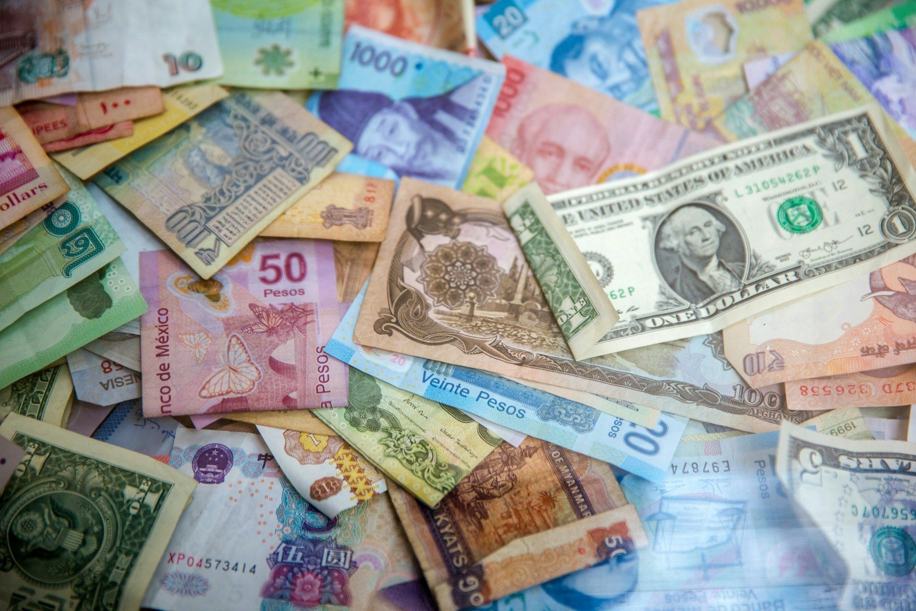 Cédulas de diferentes moedas internacionais espalhadas sobre uma superfície
