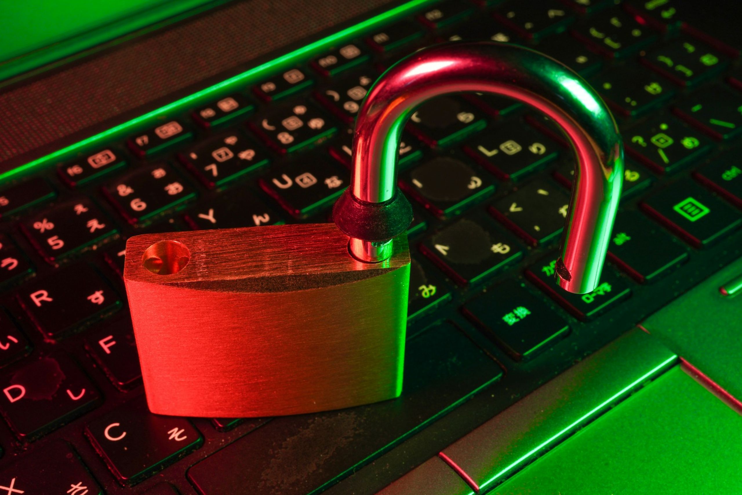Cadeado aberto sobre teclado de computador iluminado em vermelho e verde