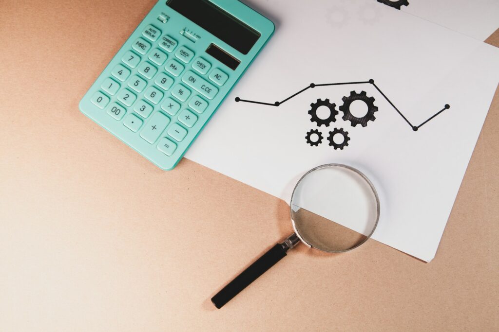 Calculadora, lupa e relatório sobre a mesa, ilustrando a análise de contratos e cálculos em ação de cobrança bancária